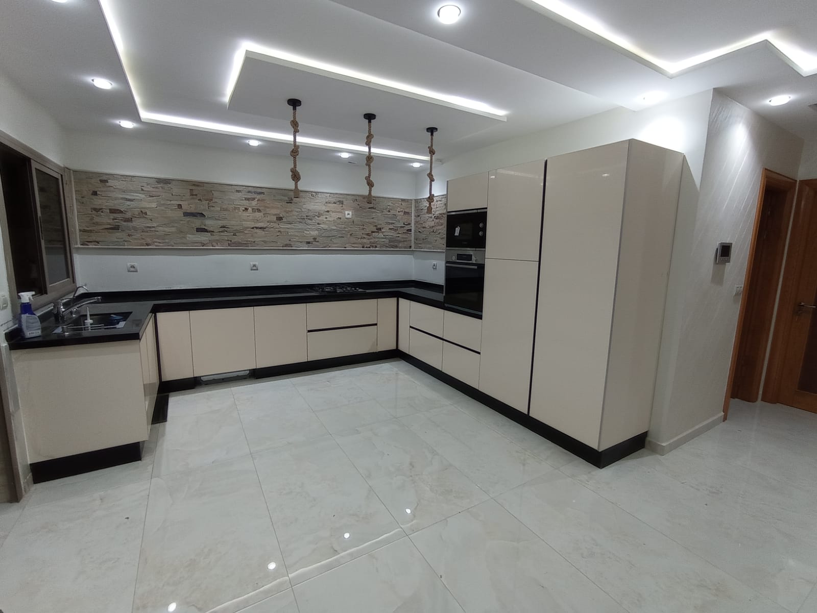 Cuisine Moderne en L – Finition Crème Laquée & Plan de Travail Noir